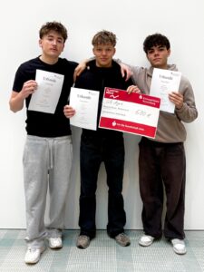 Drei Schüler präsentieren die Urkunden und den Scheck über 500 €, den sie beim Planspiel Börse gewonnen haben.