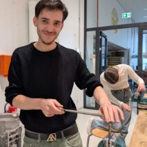 Ein Schüler bearbeitet ein Metallblech mit einer Feile.