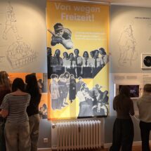 Innenansicht des Schulmuseums mit Schülerinnen, die Infotafeln studieren.