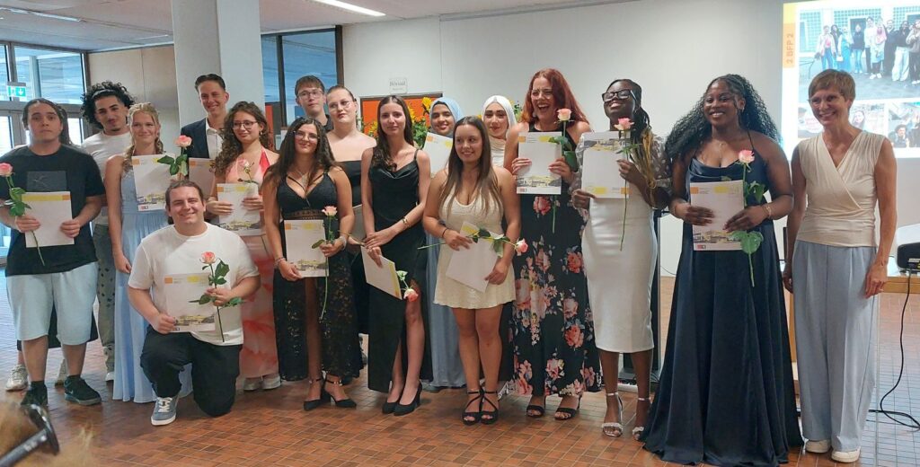 Gruppenfoto der Absolventinnen und Absolventen mit Zeugnis und Rose.