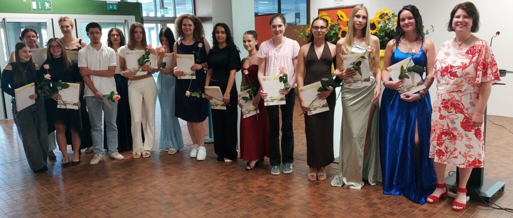 Gruppenfoto der Absolventinnen und Absolventen mit Zeugnis und Rose.