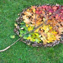 Landart aus bunten Blättern auf der grünen Wiese.