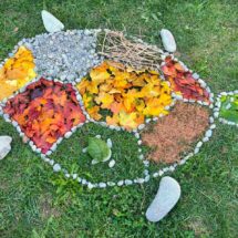 Landart aus bunten Blättern auf der grünen Wiese.
